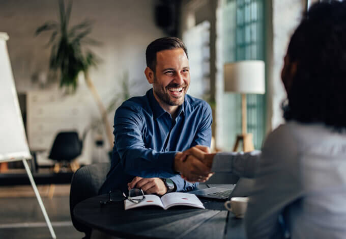 Homeowner shakes hands with loan officer during annual mortgage checkup.
