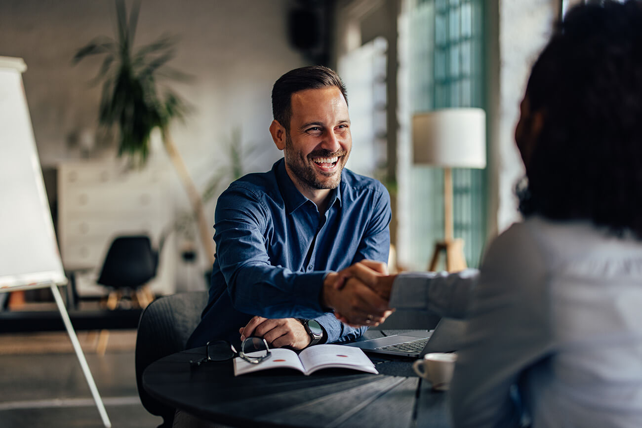Homeowner shakes hands with loan officer during annual mortgage checkup.