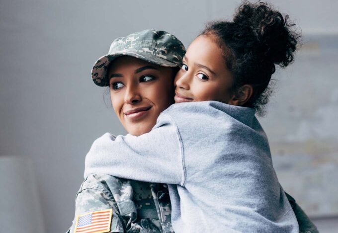 Mother in Military uniform hugs daughter inside hone purchased using VA loan.