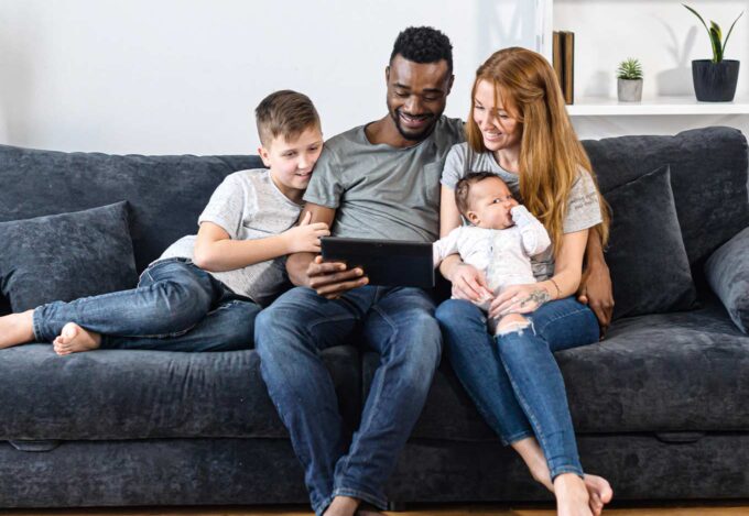 Family sitting on a couch looking to purchase a house.
