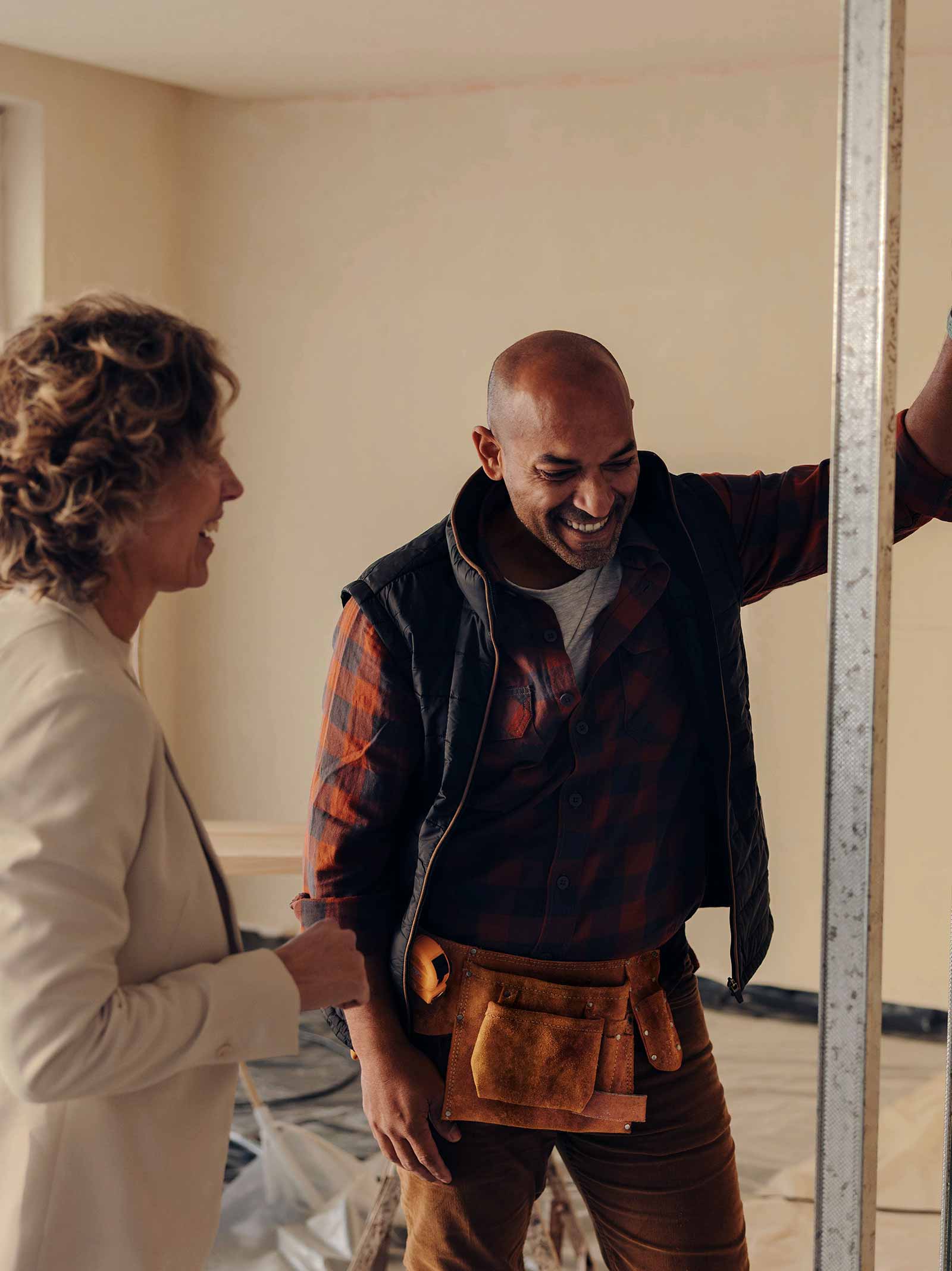 Contractor and homeowner discuss home renovations in room under construction using a cash-out refinance.