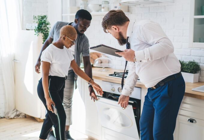 Couple Considers Renting vs. Owning With Realtor In Kitchen