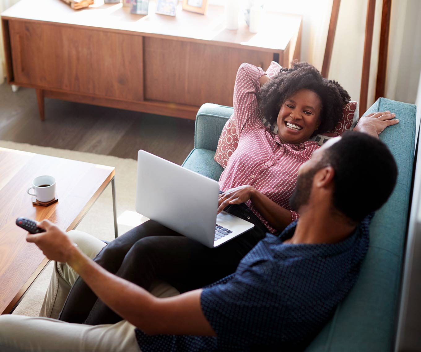 Couple relaxing on couch with laptop researches down payment assistance.