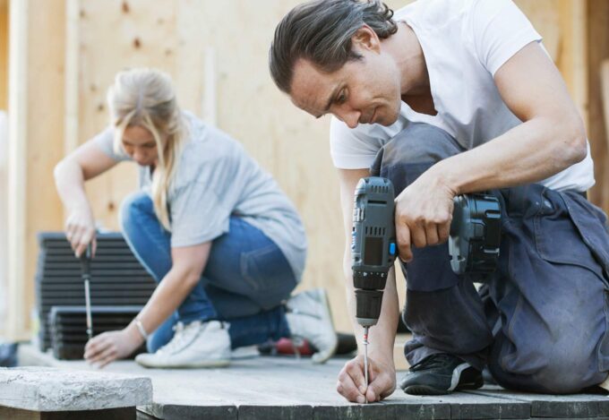 Couple outside renovating and remodeling their deck space. 