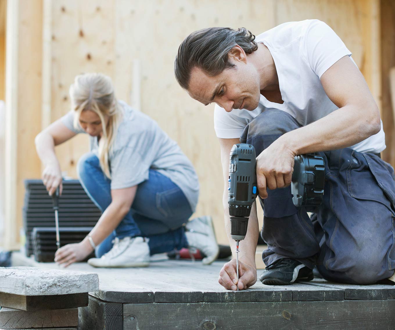 Couple outside renovating and remodeling their deck space. 
