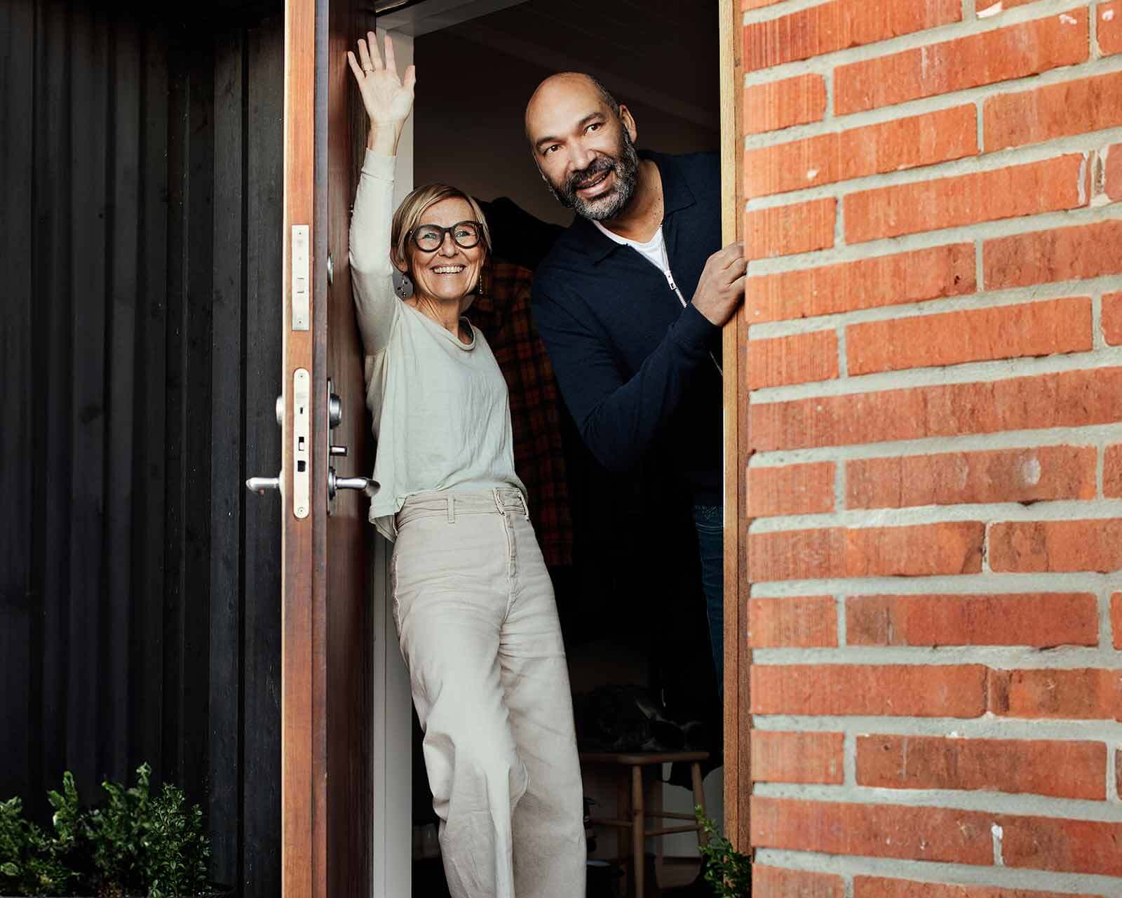 Couple standing in doorway waves bye bye together to private mortgage insurance (PMI.)