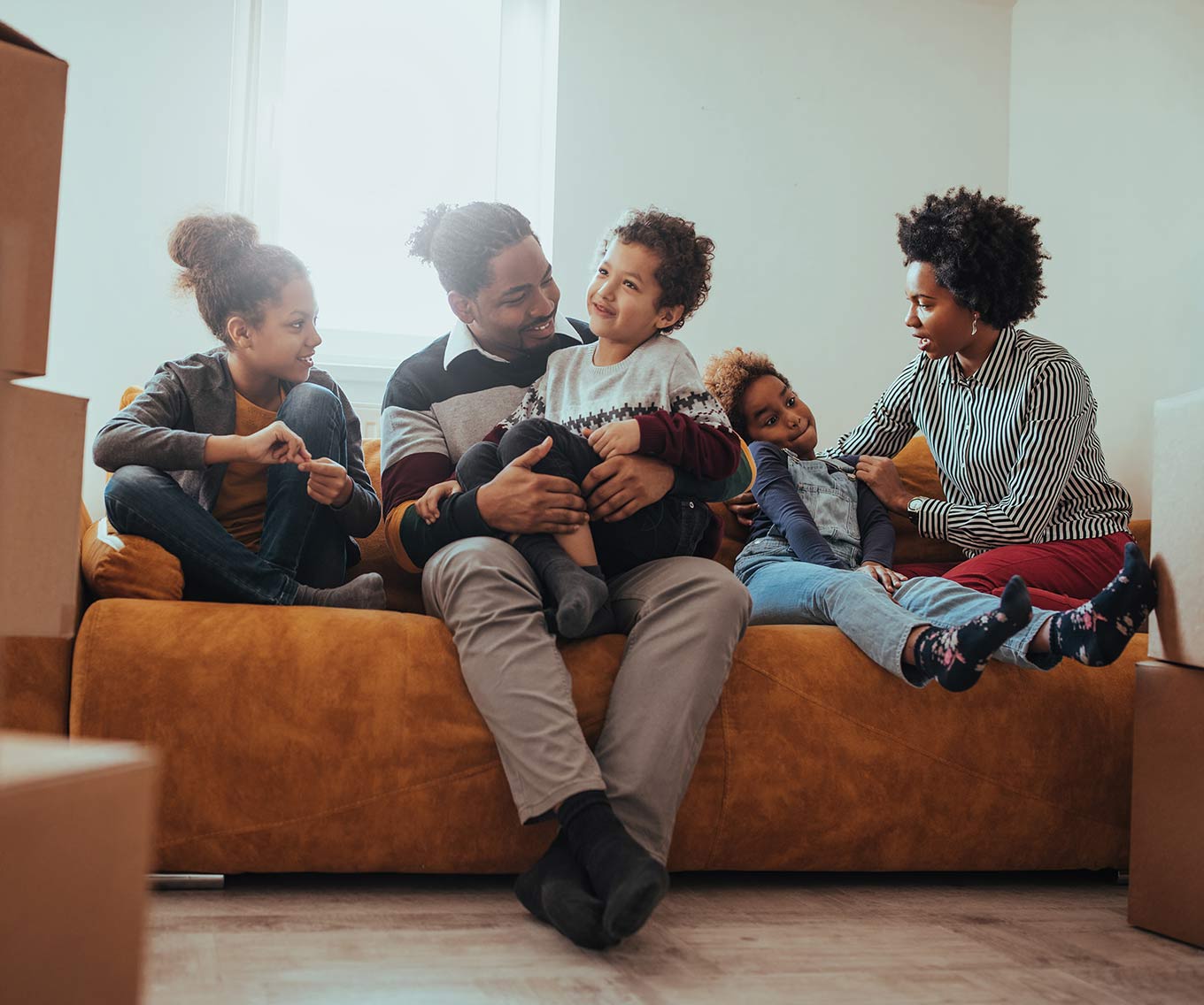 Family sits together on couch after moving into new home purchased a Fannie Mae loan program.
