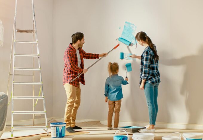 Family painting a wall and doing renovations on their fixer-upper.