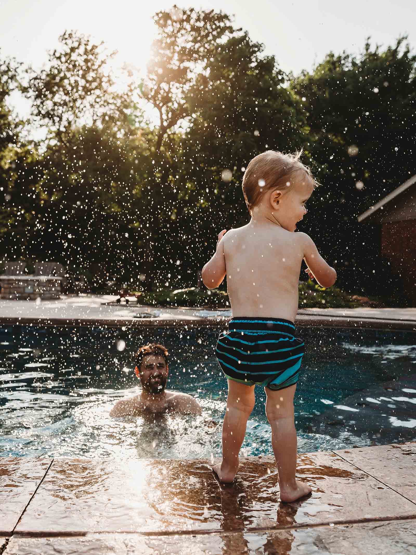 Father and son play together in a new pool installed using a conventional renovation loan.