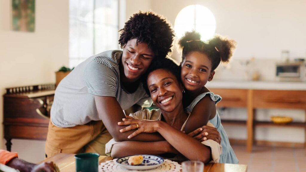 A first-timehomebuyer family including a mother and two children hug to celebrate closing and homeownership.