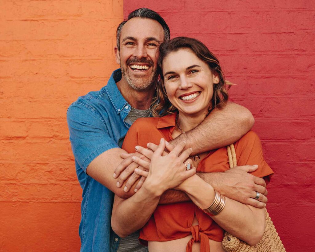 Happy couple embraces and smiles at camera after locking mortgage interest rate.