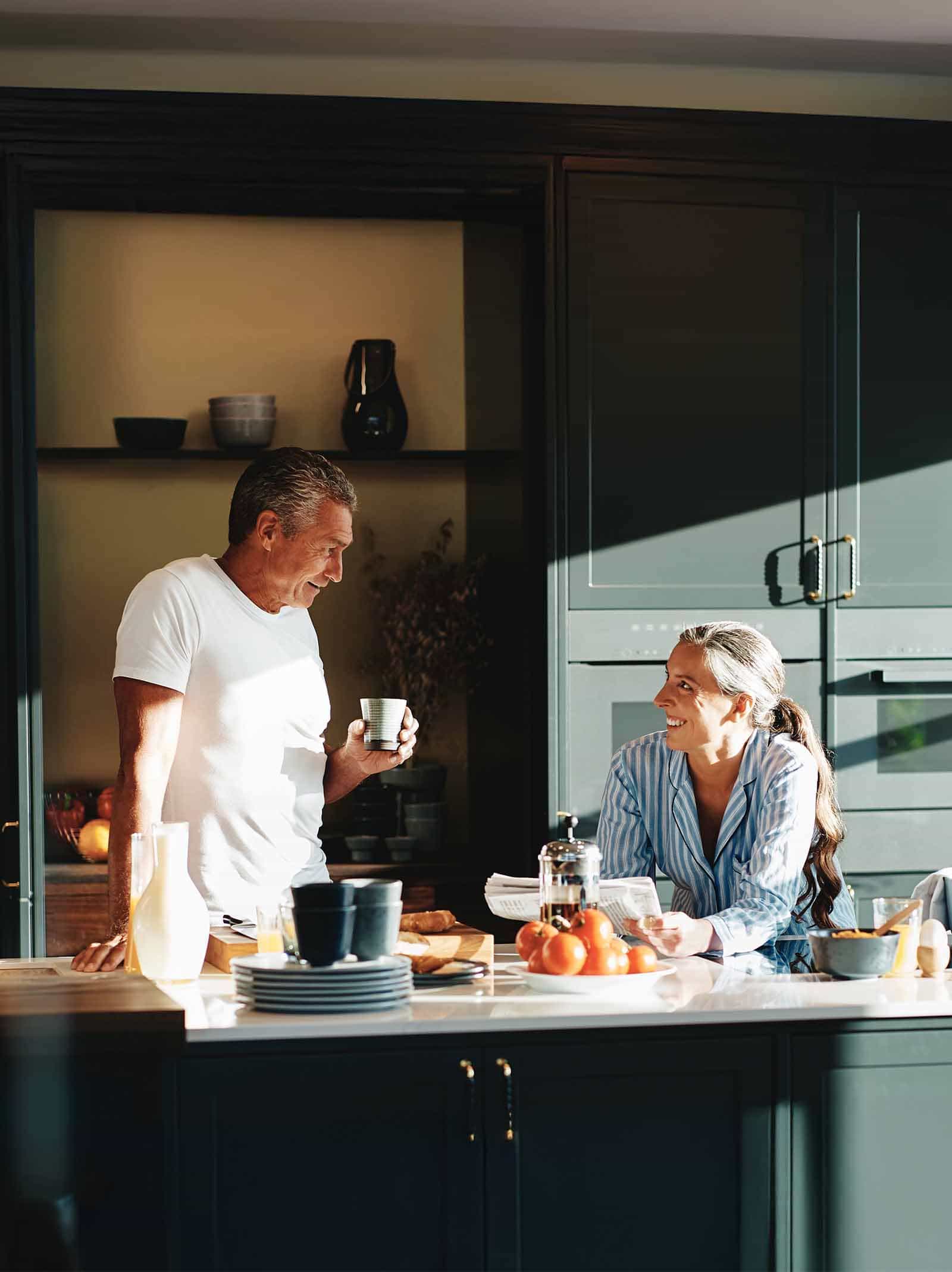 Retired couple standing in kitchen discuss purchasing a new home using HEMC and jumbo reverse loans.