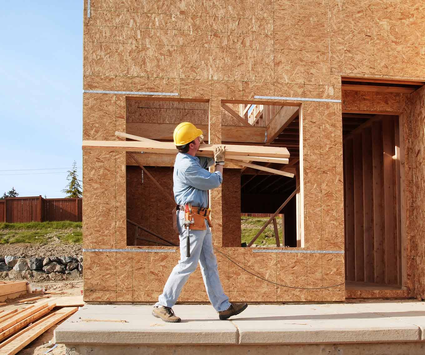 Worker carries wood for a home construction project.