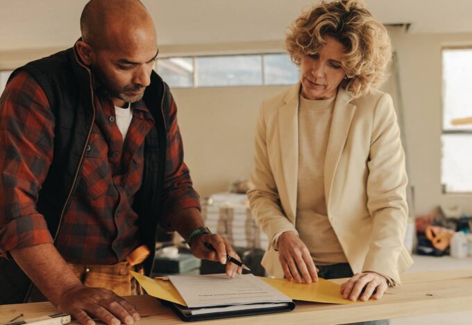 Homeowner stands with a contractor to review details of a home renovation loan.