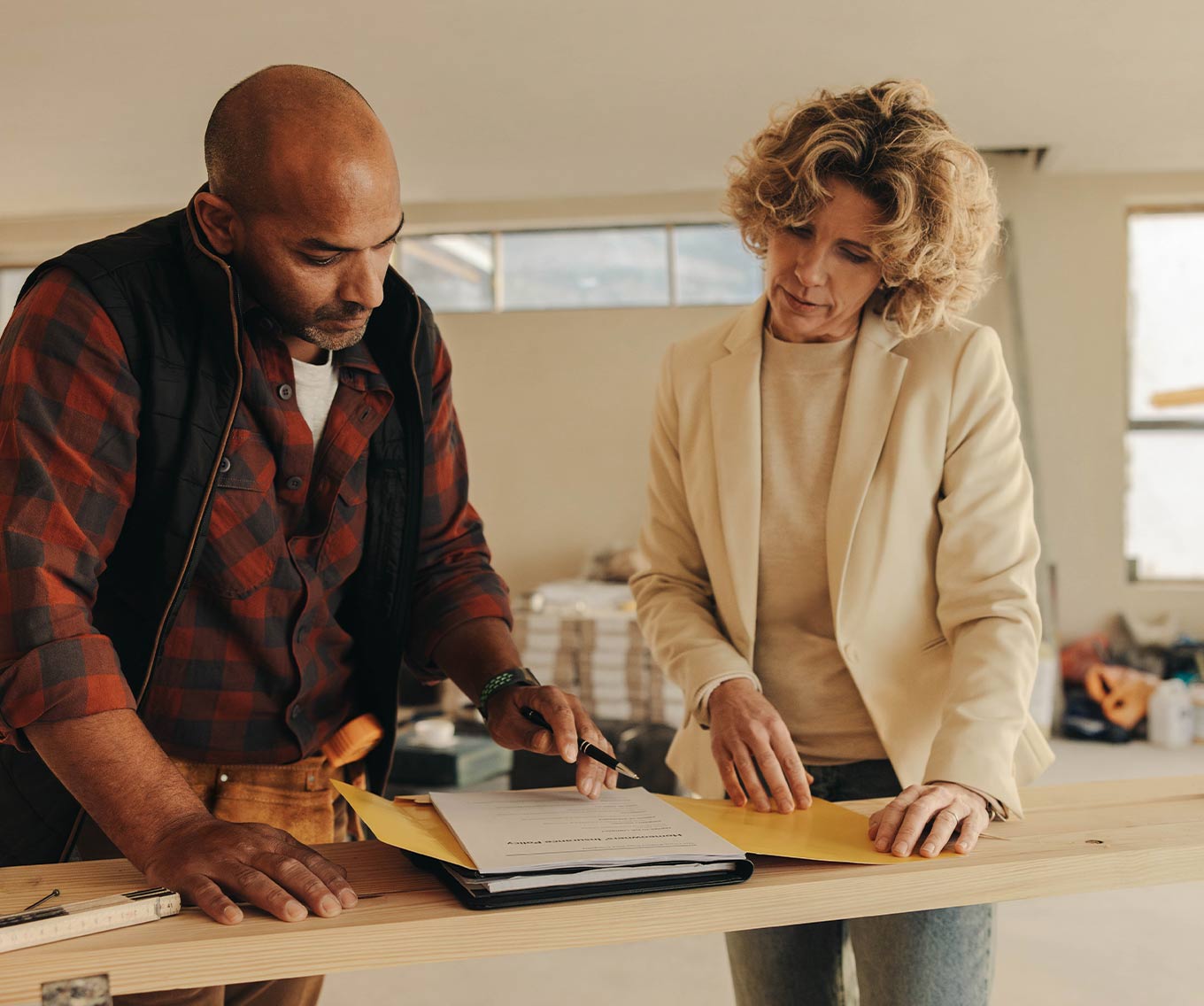 Homeowner stands with a contractor to review details of a home renovation loan.