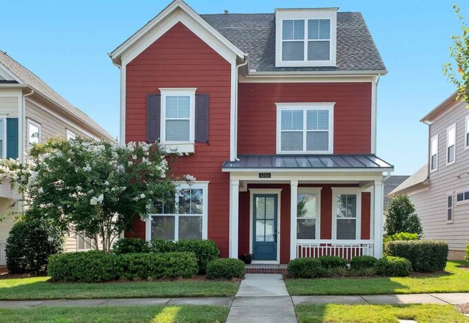 Suburban, 3-story home with red siding and black shutters.