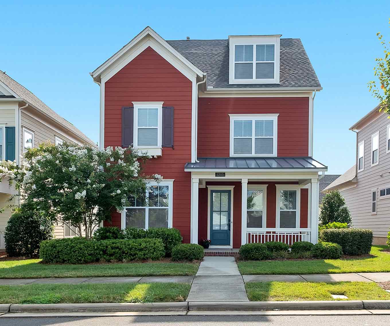 Suburban, 3-story home with red siding and black shutters.