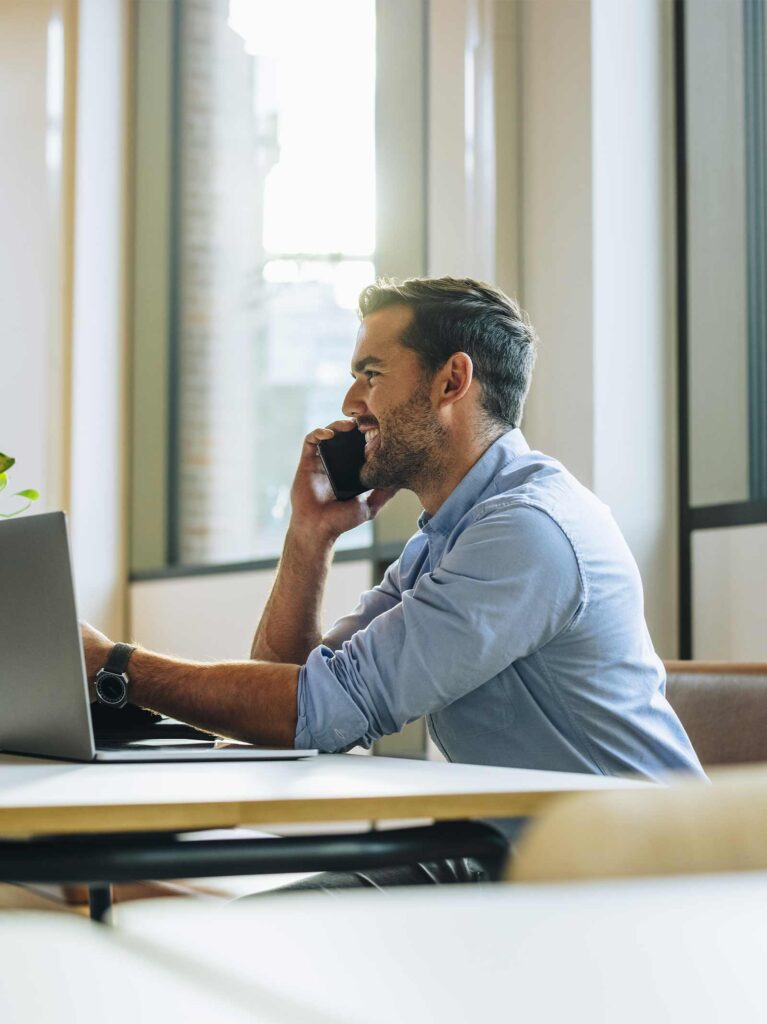 Man on cell phone at coffee shop learns about the down payment assistance programs available.