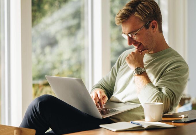 Man uses laptop to find the right home in his real estate housing search.