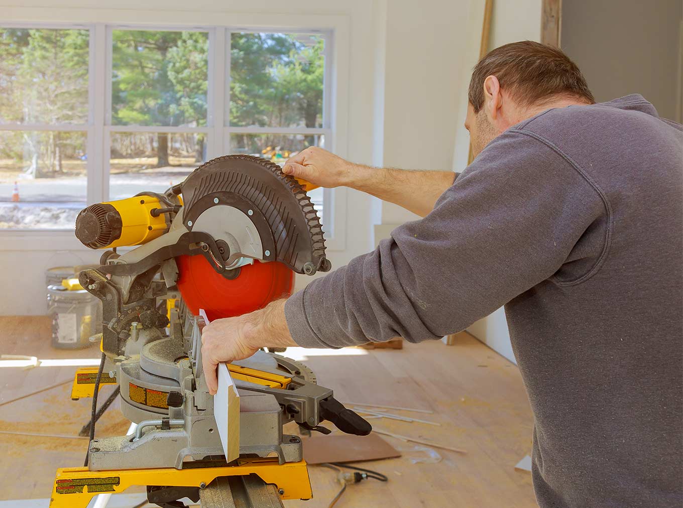 Image of a man using a saw while doing a home improvement project.