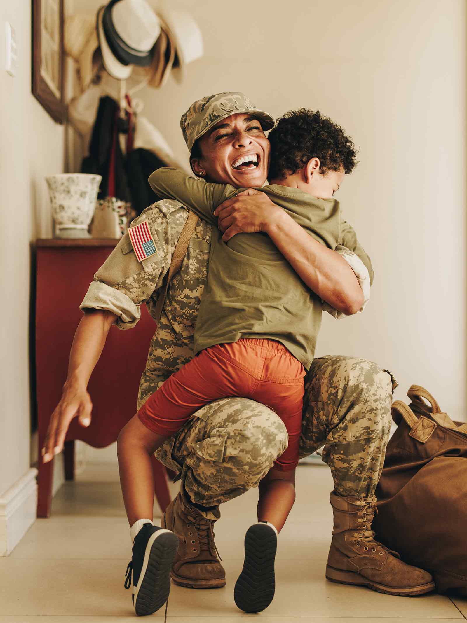 Active-Duty Military member embraces son inside front entrance to home updated using a VA renovation loan.