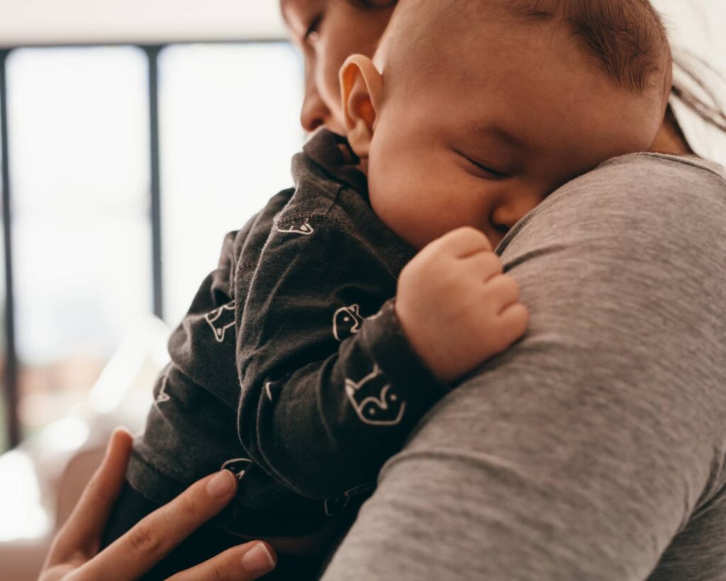 Mother holds baby inside new home purchased with low down payment program.