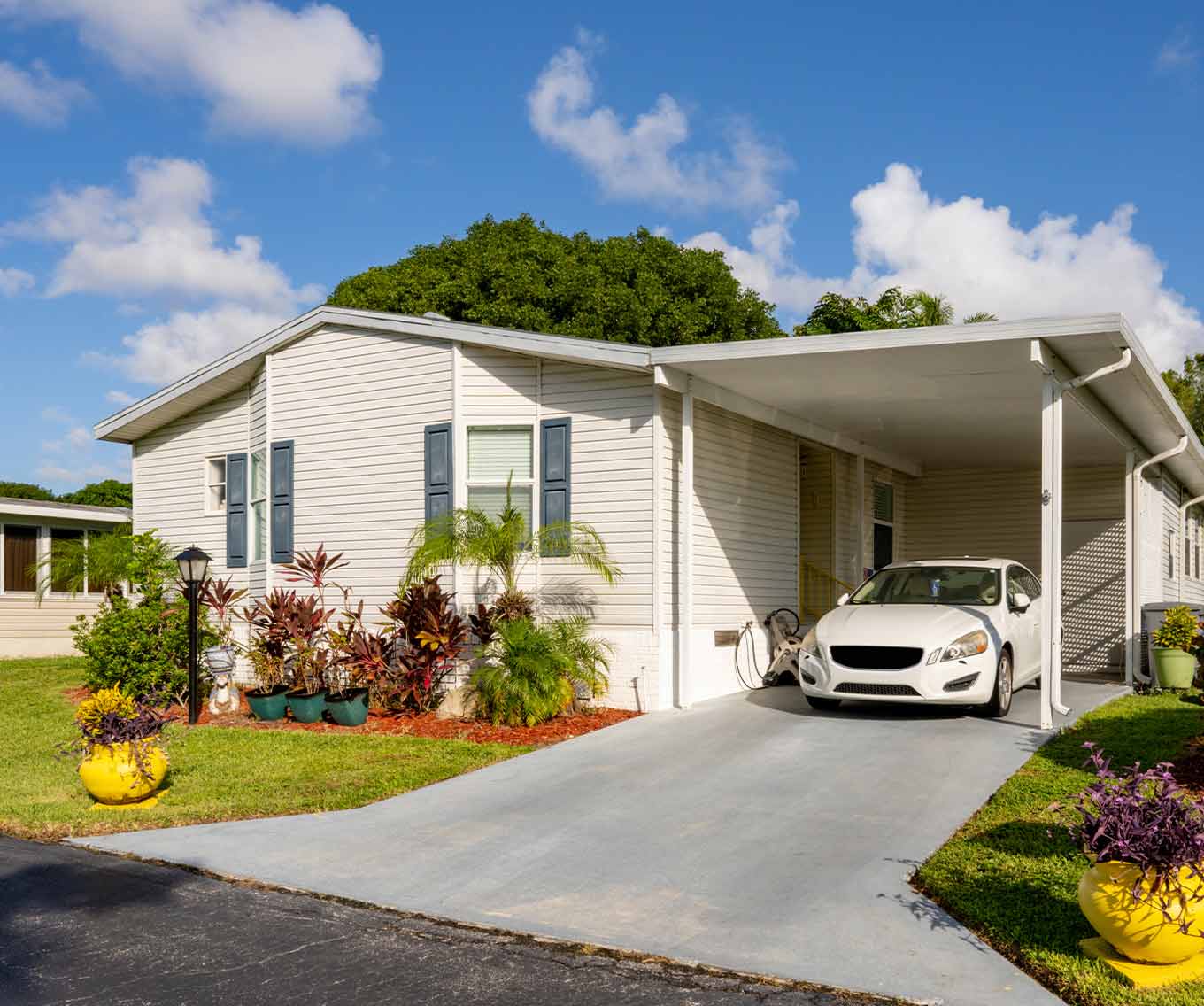 Outside of manufactured home with a car sitting in carport.