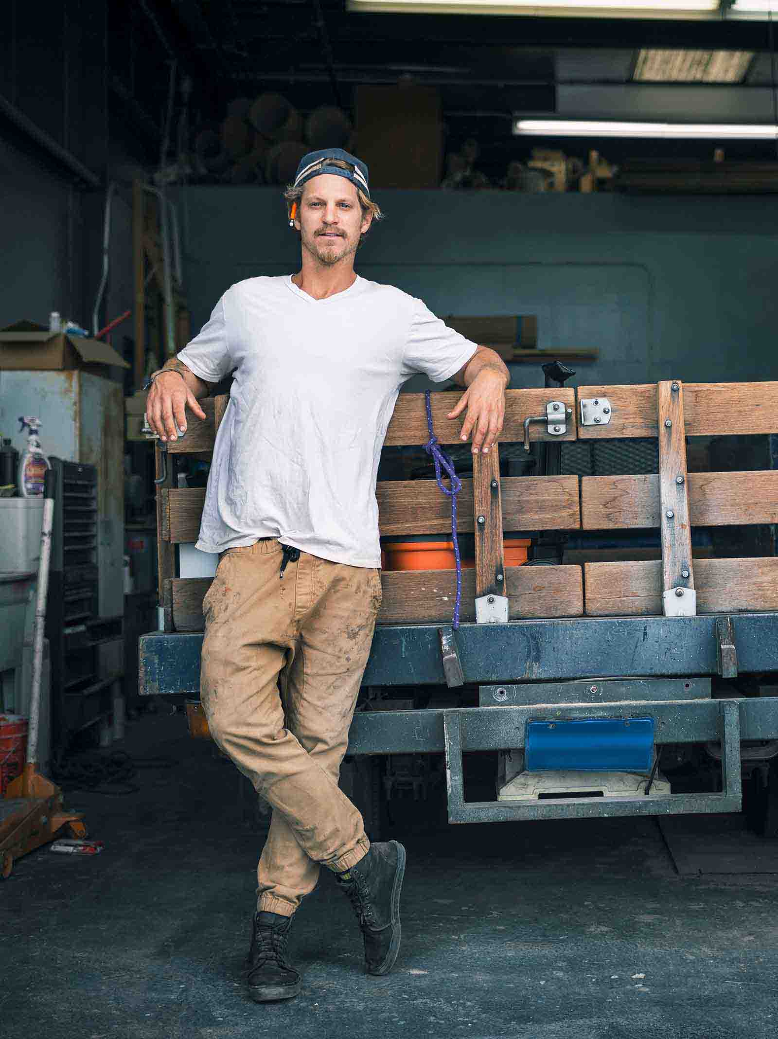A self-employed, 1099 contract worker poses in their garage surrounded by work materials.