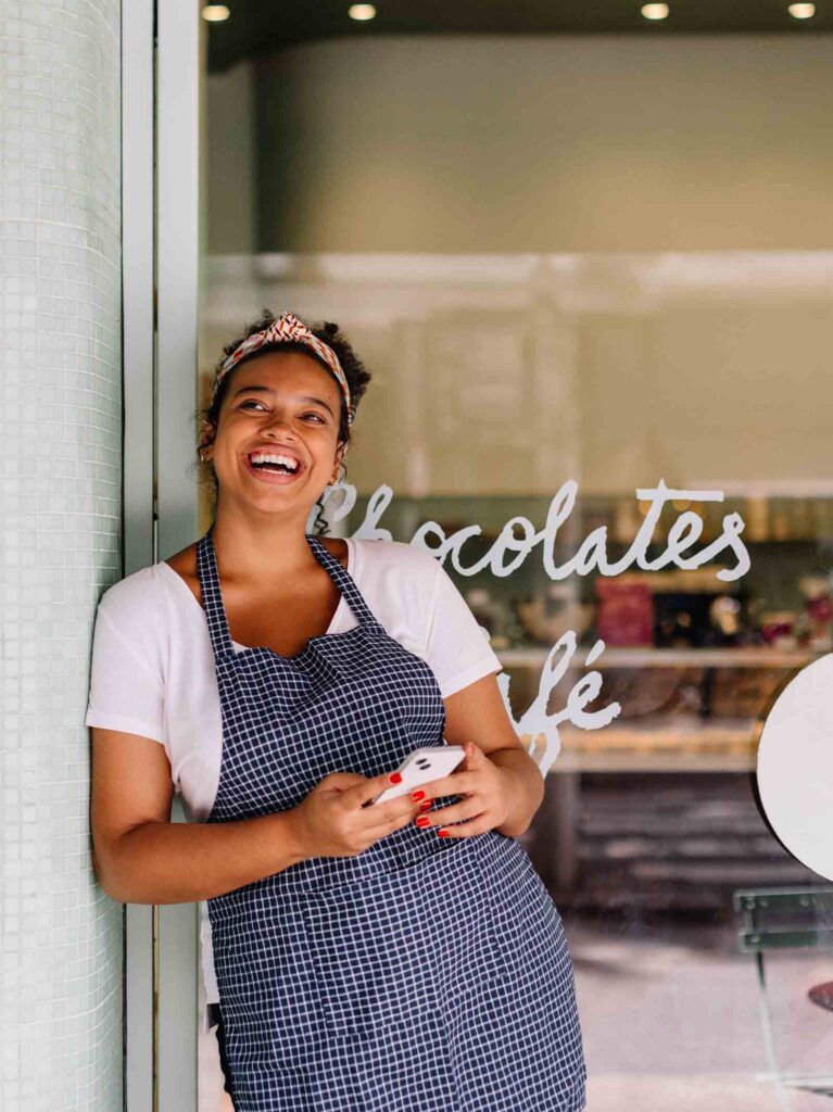 Self-employed chocolate shop owner posts in front of store.