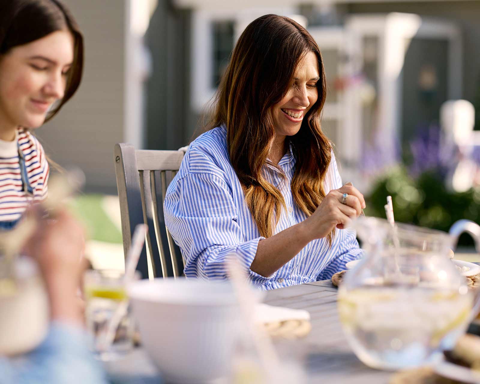 Woman sits outside eating at a picnic table in the backyard of home recently refinanced.